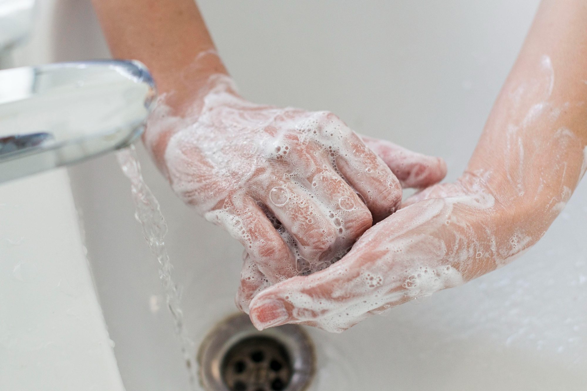 soapy hands under a sink faucet