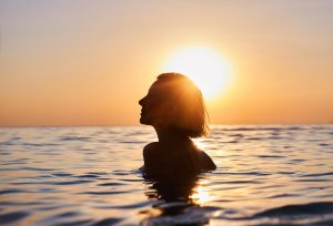 content woman in water as at sunset