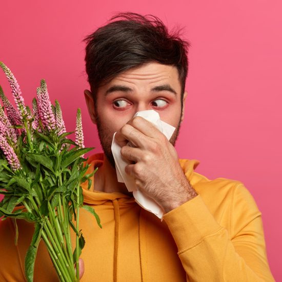 man holding flowers and tissue with visible allergies