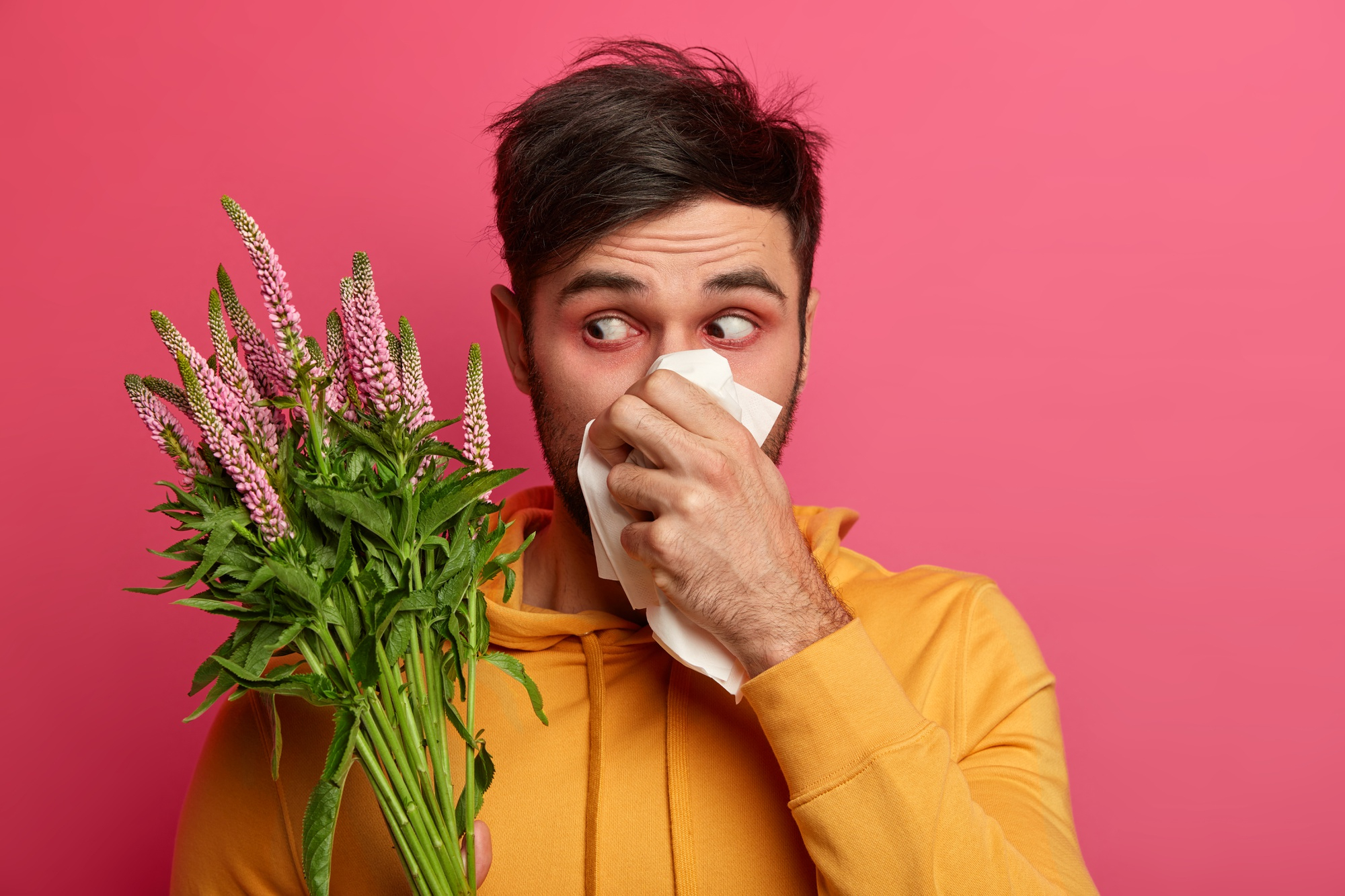 man holding flowers and tissue with visible allergies